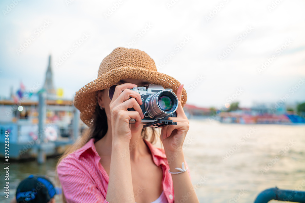 Beautiful woman take photo with camera travel in city river side
