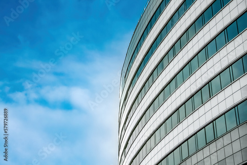 The facade of a modern building at an angle against a blue sky. Background image