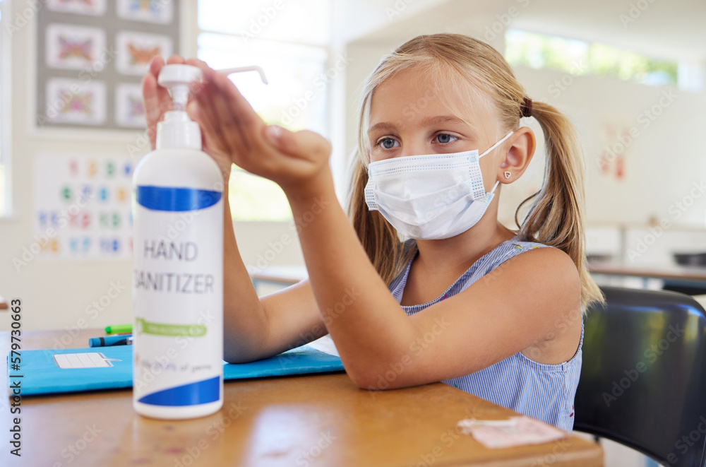 Little student sanitizing hand to protect from covid, wearing a mask and following new hygiene safety routine. Kindergarten or preschool female learner protecting herself from corona virus flu