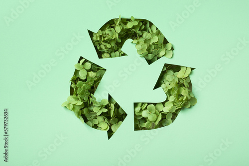 Green flowers under paper cut recycling symbol. Save planet recycling cloth concept