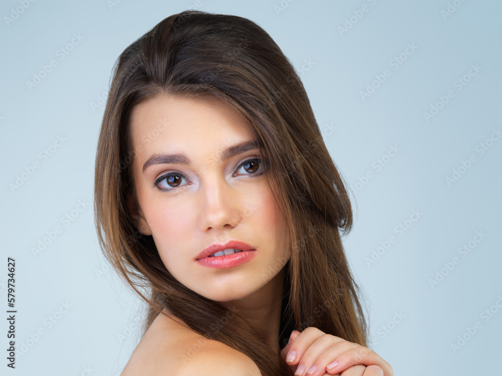 Naklejka premium Hair, serious and portrait of woman with makeup on blue background for wellness, skincare and facial treatment. Salon aesthetic, dermatology and face of girl with cosmetics, beauty and confidence