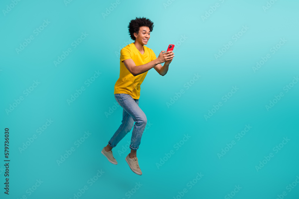 Full size portrait of overjoyed crazy person jump run use telephone isolated on turquoise color background Full size portrait of overjoyed crazy person jump run use telephone isolated on turquoise color background