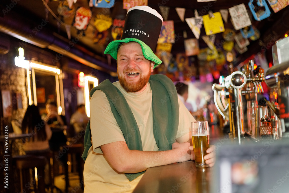 funny ginger man in leprechaun hat for st patrick's day in pub