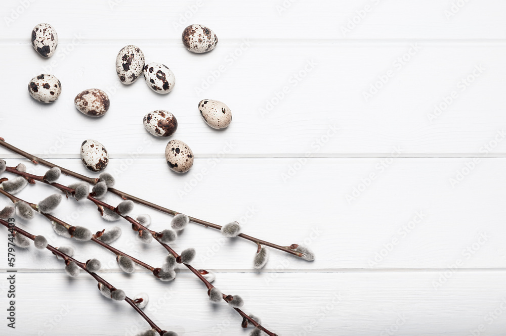 Fototapeta premium Quail eggs and willow branches on a white wooden table. Easter background.