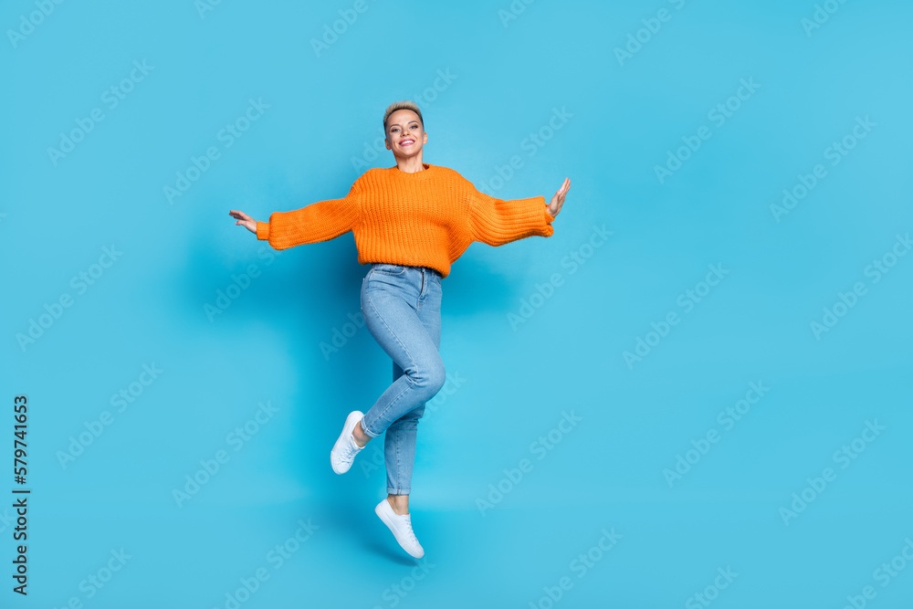 Full length photo of cute excited pretty dressed knitted pullover jumping high empty space isolated blue color background