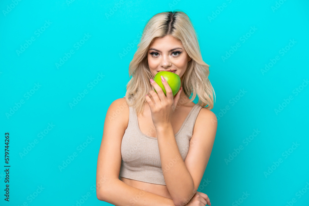 Young Russian woman isolated on blue background eating an apple Young Russian woman isolated on blue background eating an apple