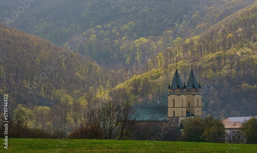 Medieval monastery in Hronsky Benadik (Slovakia), ancient Gothic building, spring nature, orchard. Gothic church in the mountains. Discover the spring beauty of nature and old architecture.