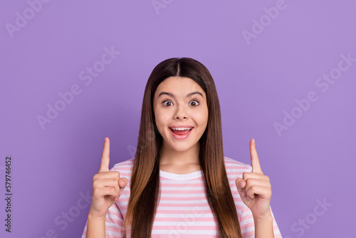 Photo of charming impressed girl dressed striped white pink t-shirt pointing up empty space isolated purple color background