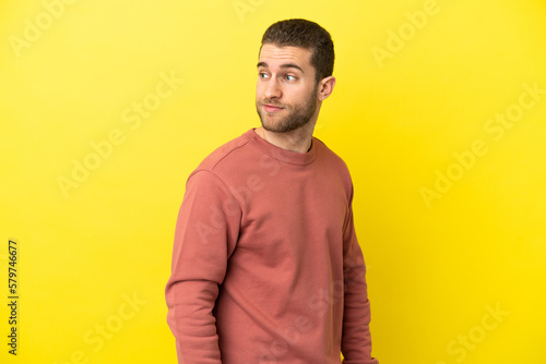 Handsome blonde man over isolated yellow background . Portrait