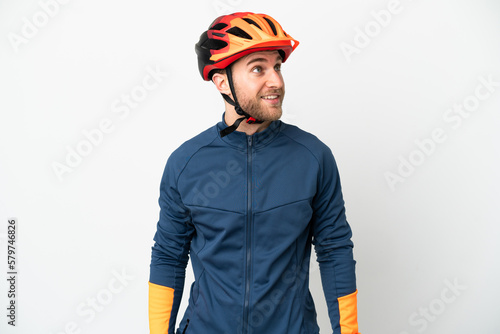 Young cyclist man isolated on white background thinking an idea while looking up