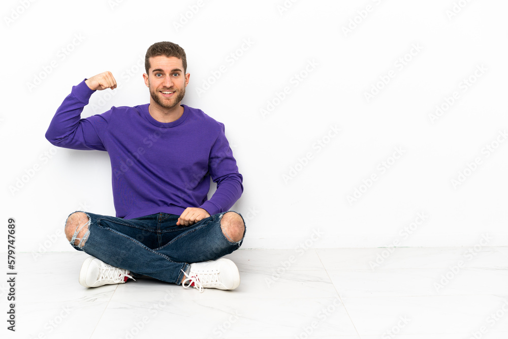 Young man sitting on the floor doing strong gesture Young man sitting on the floor doing strong gesture