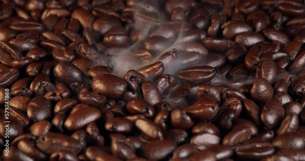 Macro shot roasting coffee beans, filmed in a dark key the smoke emanating from the roasting of coffee beans. Fragrant coffee beans are roasted smoke comes from coffee beans. Macro shot roasting coffee beans, filmed in a dark key the smoke emanating from the roasting of coffee beans. Fragrant coffee beans are roasted smoke comes from coffee beans.