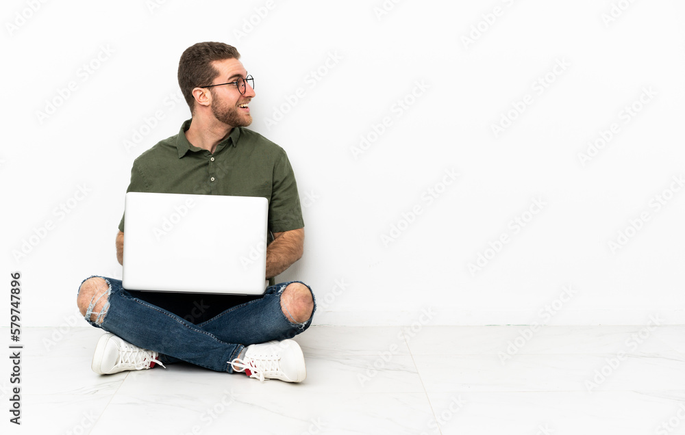 Young man sitting on the floor laughing in lateral position Young man sitting on the floor laughing in lateral position