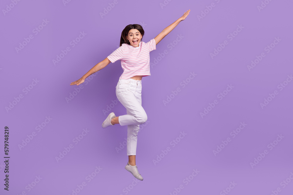 Full size photo of overjoyed active girl jumping empty space ad isolated on violet color background