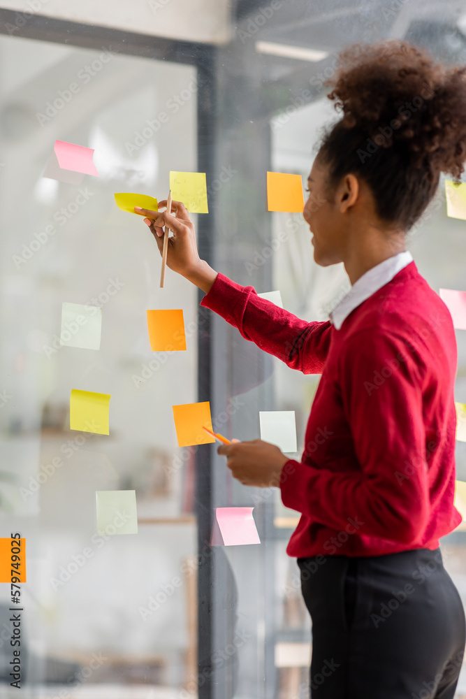 Young mixed african american businesswoman with afro hairstyle planning on whiteboard in a startup brainstorming strategies workplace office Young mixed african american businesswoman with afro hairstyle planning on whiteboard in a startup brainstorming strategies workplace office
