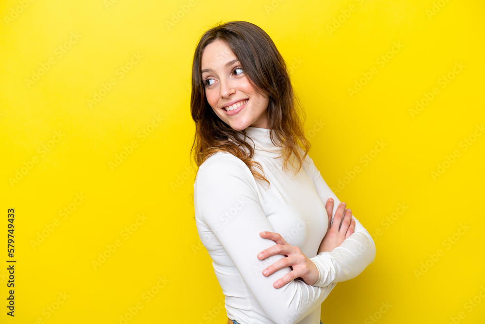 Young caucasian woman isolated on yellow background looking to the side and smiling Young caucasian woman isolated on yellow background looking to the side and smiling