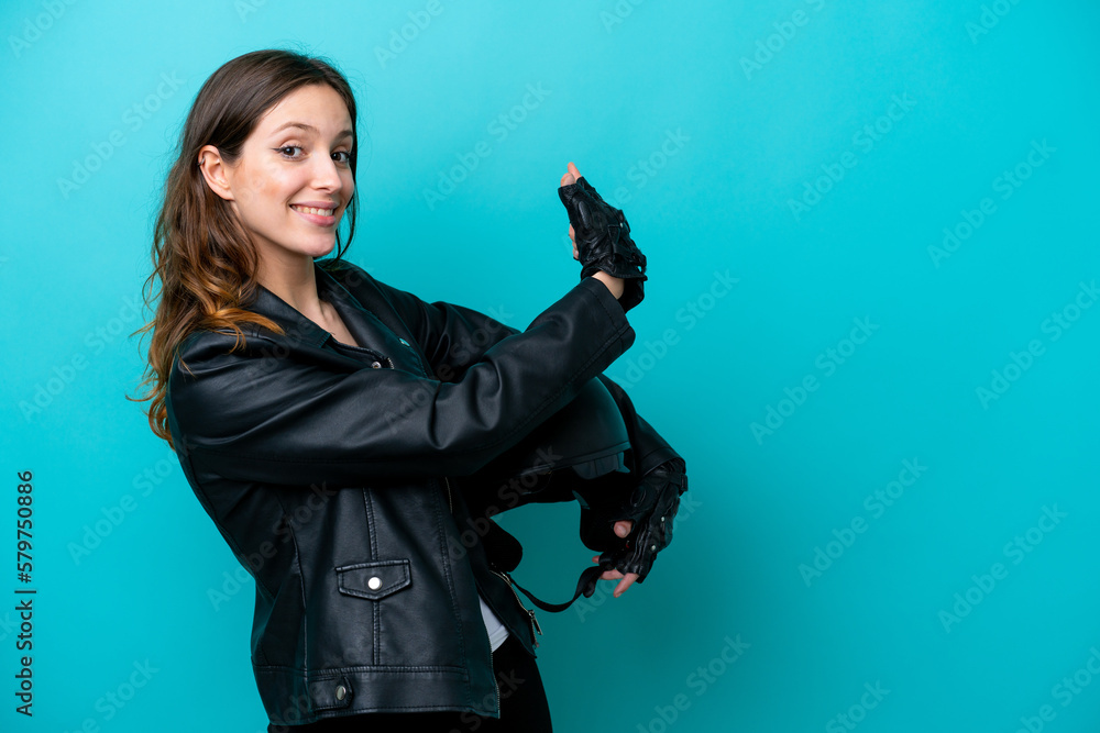 Young caucasian woman with a motorcycle helmet isolated on blue background pointing back Young caucasian woman with a motorcycle helmet isolated on blue background pointing back