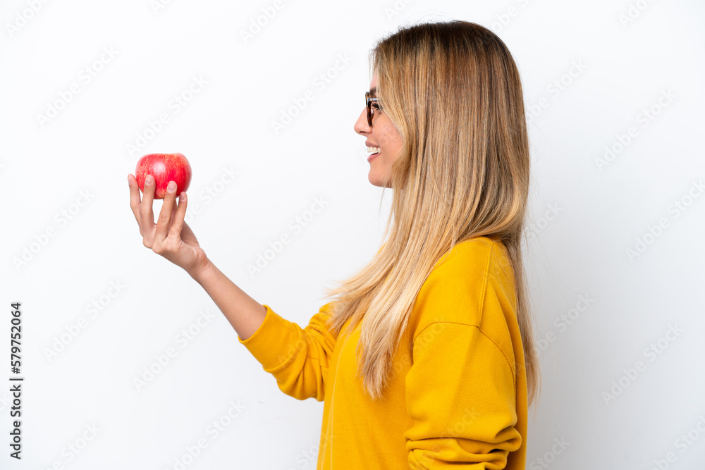 Young Uruguayan woman with an apple isolated on white background with happy expression Young Uruguayan woman with an apple isolated on white background with happy expression
