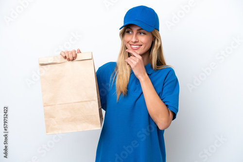 Young Uruguayan woman taking a bag of takeaway food isolated on white background looking to the side and smiling