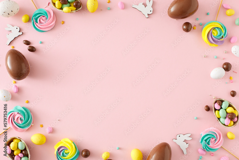 Easter sweets concept. Top view photo of chocolate eggs dragees cute bunnies meringue lollipops and sprinkles on isolated pastel pink background with copyspace in the middle