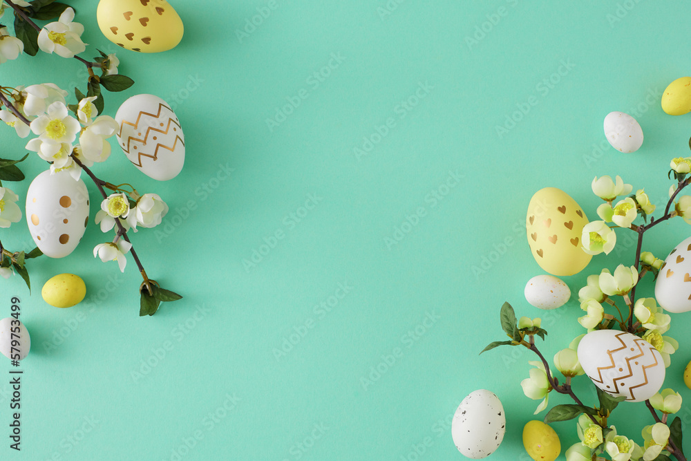Easter decoration concept. Top view photo of yellow white easter eggs and cherry blossom branches on turquoise background with copyspace