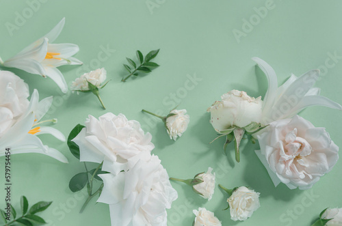 Creative summer composition made of rose and lily flowers on pastel green background. Beautiful floral layout. Nature concept. Top view. Flat lay