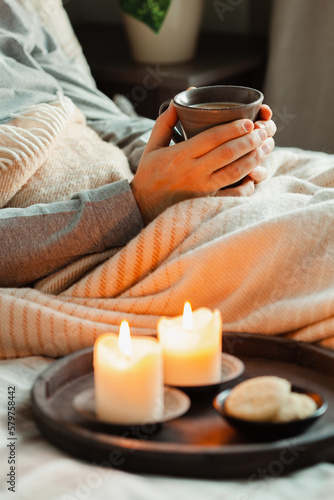 Obraz na płótnie A caucasian man relaxing at home, lighting candle, drinking coffee in bed under blanket w salonie
