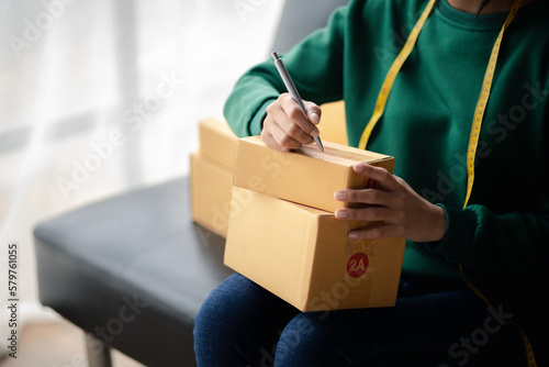 A business owner opens an online store, she is checking orders from customers, sending goods through a courier company, concept of a woman opening an online business.