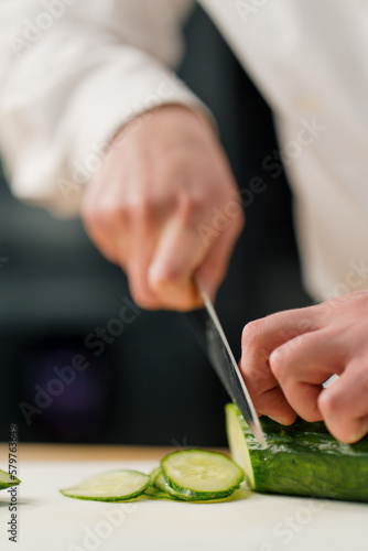 Chef cuts a cucumber on a cutting board close-up slice of cucumber close-up professional kitchen