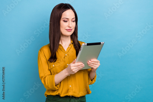 Photo of charming confident lady dressed yellow shirt reading news modern gadget emtpy space isolated blue color background