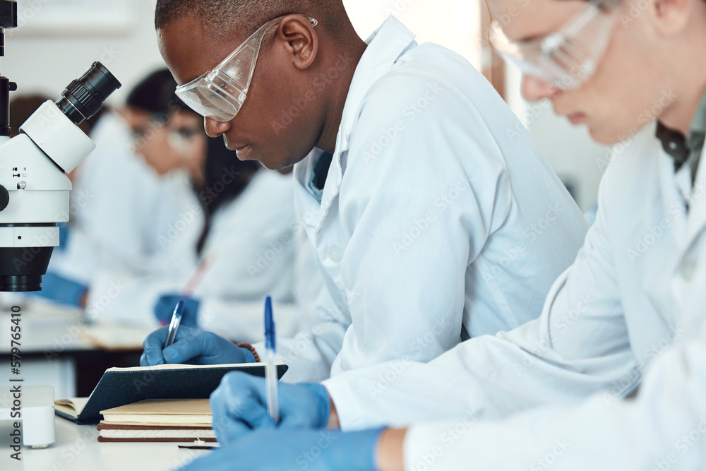 Science students, research and writing in laboratory, experiment and healthcare innovation. Researchers, notebooks and make notes for medical scientific methods, exams and analysis for cure and focus Science students, research and writing in laboratory, experiment and healthcare innovation. Researchers, notebooks and make notes for medical scientific methods, exams and analysis for cure and focus