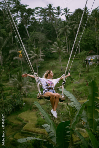 Rear view woman on a swing at vacation in Bali, Indonesia. Young girl traveler sitting on the swing in beautiful nature place in the mountains, tropical jungle view