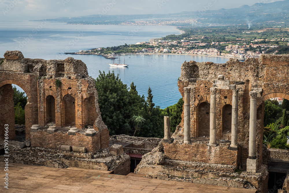 Ancient town Taormina in Sicily, Italy with antique theatre in Mediterranean and port