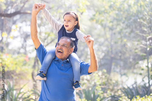 Carefree granddaughter carrying grandson on shoulders at park