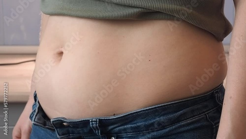 The woman draws in her stomach and inflates. Relax and tighten your abdominal muscles. White European girl in jeans and bare stomach.