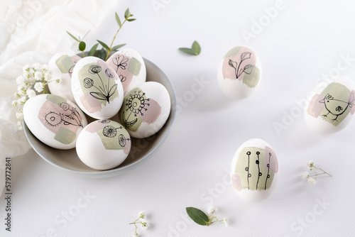 Bowl with modern creative trendy  hand painted easter egg in spring flowers on white background.  Homemade tradition Easter ideas. Greeting card