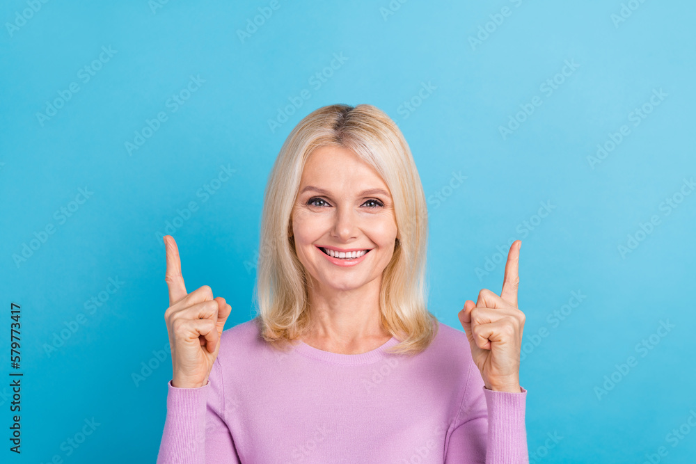 Photo of cheerful adorable senior lady wear stylish clothes two arm direct empty space opening clinic isolated on blue color background Photo of cheerful adorable senior lady wear stylish clothes two arm direct empty space opening clinic isolated on blue color background