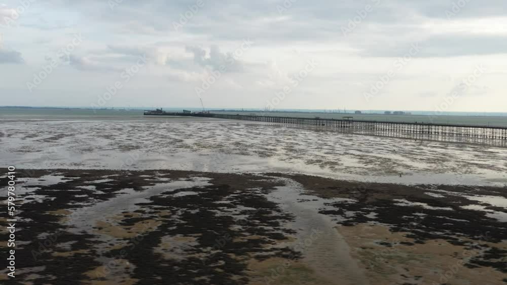 Wet sea coast at low tide. Long Southend Pier in Thames river estuary in background. Southend-on-Sea, UK Wet sea coast at low tide. Long Southend Pier in Thames river estuary in background. Southend-on-Sea, UK