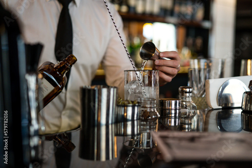 A young man bartender works in a bar made a cocktail.
