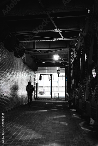 Fotografija Black and white photo of shadowy figure walking behind under a passageway