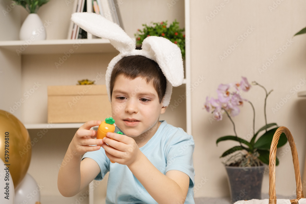 A preschool Easter boy plays with carrots, rabbit ears on his head. A preschool Easter boy plays with carrots, rabbit ears on his head.