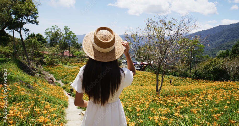 Travel woman visit Orange day lily flower field in Taimali Kinchen Mountain in Taitung