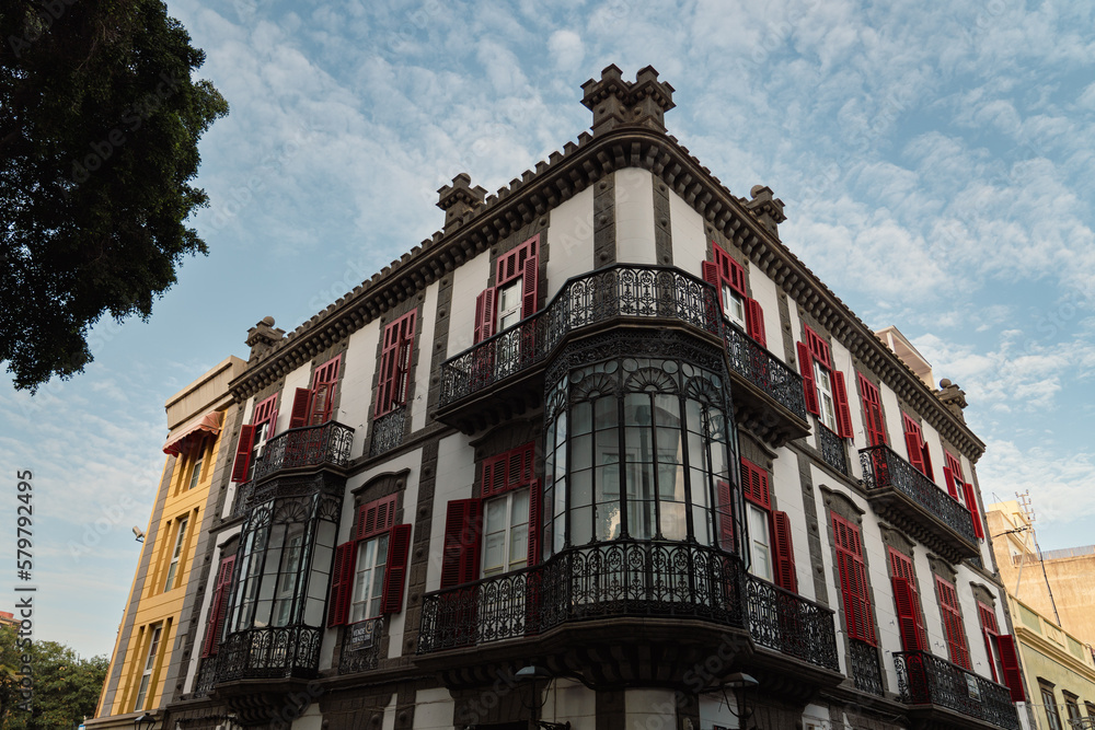 Fototapeta premium Corner view of white building with ornate windows and red shutters in old town in the city of Las Palmas de Gran Canaria, Spain