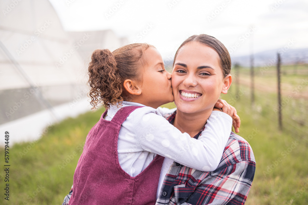 Mother, kiss and girl on a sustainability, agriculture and ecology farm with family love and care. Portrait of a mama and kid on a eco friendly, clean energy and green farming countryside with smile