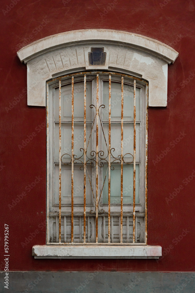 Front view of white window with metal decorative bars in red building, in old town in the city of Las Palmas de Gran Canaria, Spain