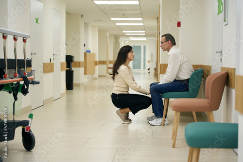 Kind young woman comforts a middle-aged man in hospital corridor