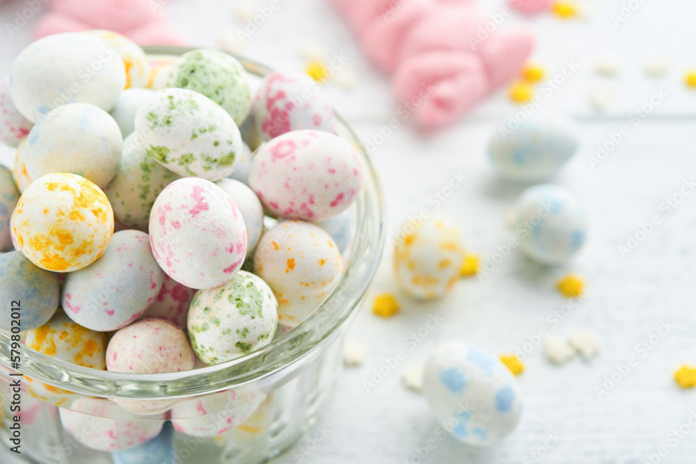 Fototapeta premium Sweet Easter concept. Sweet Easter kids holiday assortment marshmallows rabbit, chocolates easter eggs, candies, bunny, snacks on white wooden background. Flat lay Easter decoration idea. Mock up.