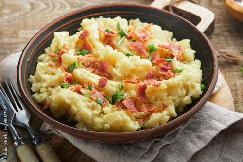 Mashed potatoes. Bacon mashed potatoes with green onion, pepper and cheddar cheese in bowl on old wooden backgrounds. Delicious creamy mashed potatoes. Top view.