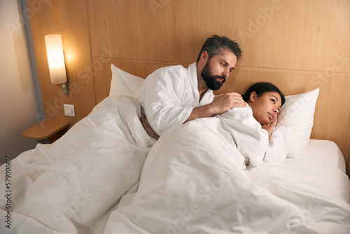 Guy comforting his sad female companion in hotel room