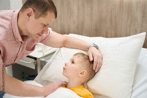 Handsome Caucasian dad is soothing the child in the modern hospital
